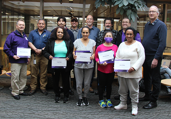 Group of a dozen people holding up certificates